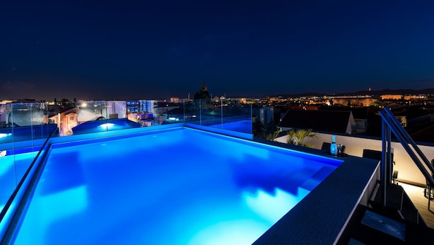Una piscina infinita en la azotea con vistas despejadas del horizonte urbano nocturno.
