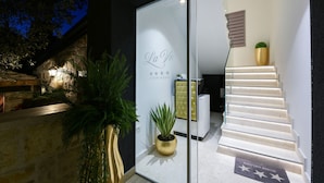 Una entrada de hotel moderna con fachada de vidrio, una escalera que conduce al interior y un letrero que dice "La Vie Luxury Rooms".