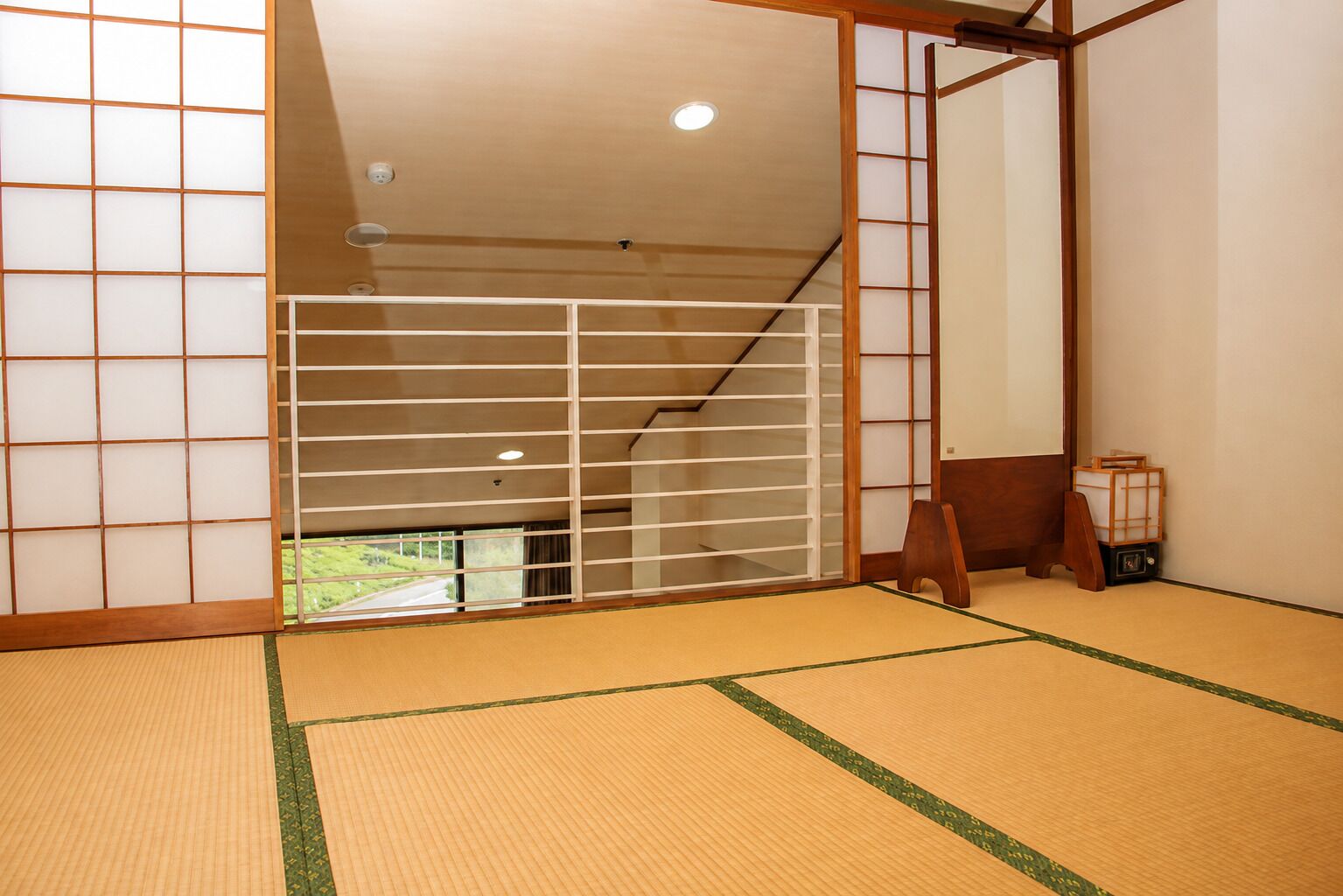 Una habitación tradicional japonesa con suelo de tatami, puertas correderas shoji y vistas a un paisaje verde.