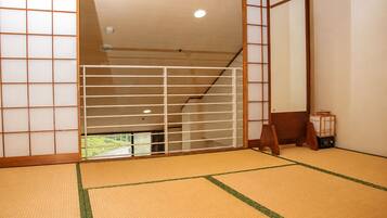 Una habitación tradicional japonesa con suelo de tatami, puertas correderas shoji y vistas a un paisaje verde.
