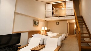 Une chambre d’hôtel avec une télévision, deux lits, un balcon et un escalier.
