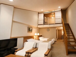 Une chambre d’hôtel avec une télévision, deux lits, un balcon et un escalier.