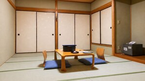 Une pièce de style japonais traditionnel, avec un sol recouvert de tatamis, une basse table en bois entourée de coussins et des portes coulissantes en papier de riz (shoji).
