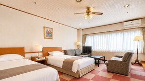 Une chambre d’hôtel avec deux lits, un canapé, une télévision, un bureau et une chaise.