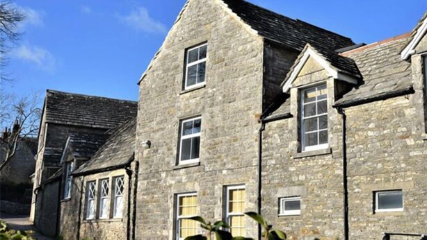 A stone building with multiple windows and a sloped roof. - Mallow Cottage (Swanage)