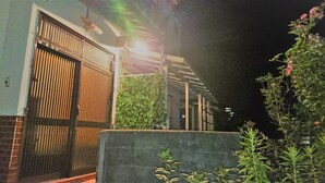 A gated entrance with a metal gate, a concrete wall, and a small garden area with plants. - The Sloope Nagasaki (Nagasaki)