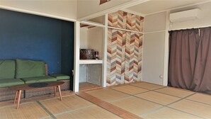 A room with a green sofa, a small wooden table, a patterned wall, and a sliding door. - The Sloope Nagasaki (Nagasaki)