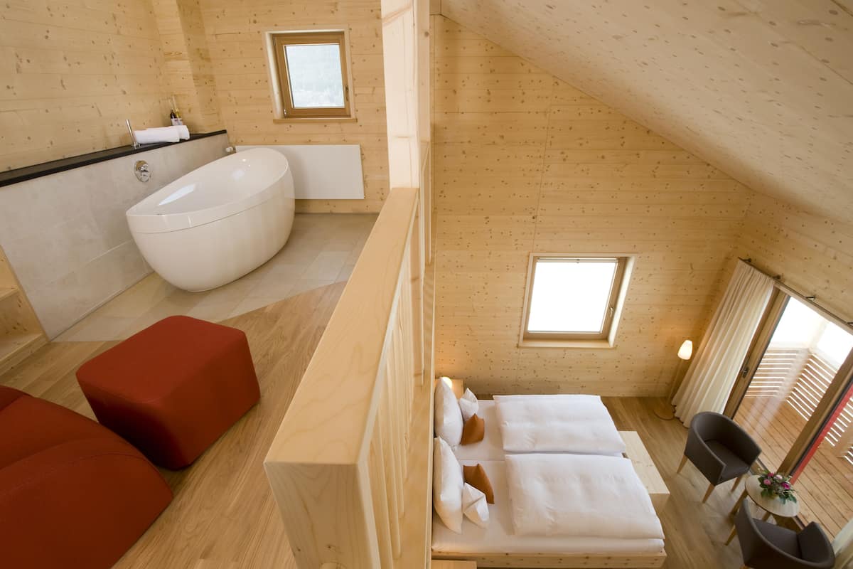 Een houten interieur met een bad, twee bedden en een rode bank.