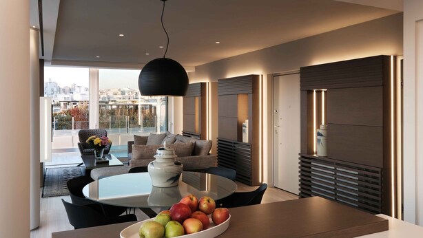 A modern dining area with a round table, a bowl of fruit, and a pendant light. - Sunlight Acropolis Loft (Athens)