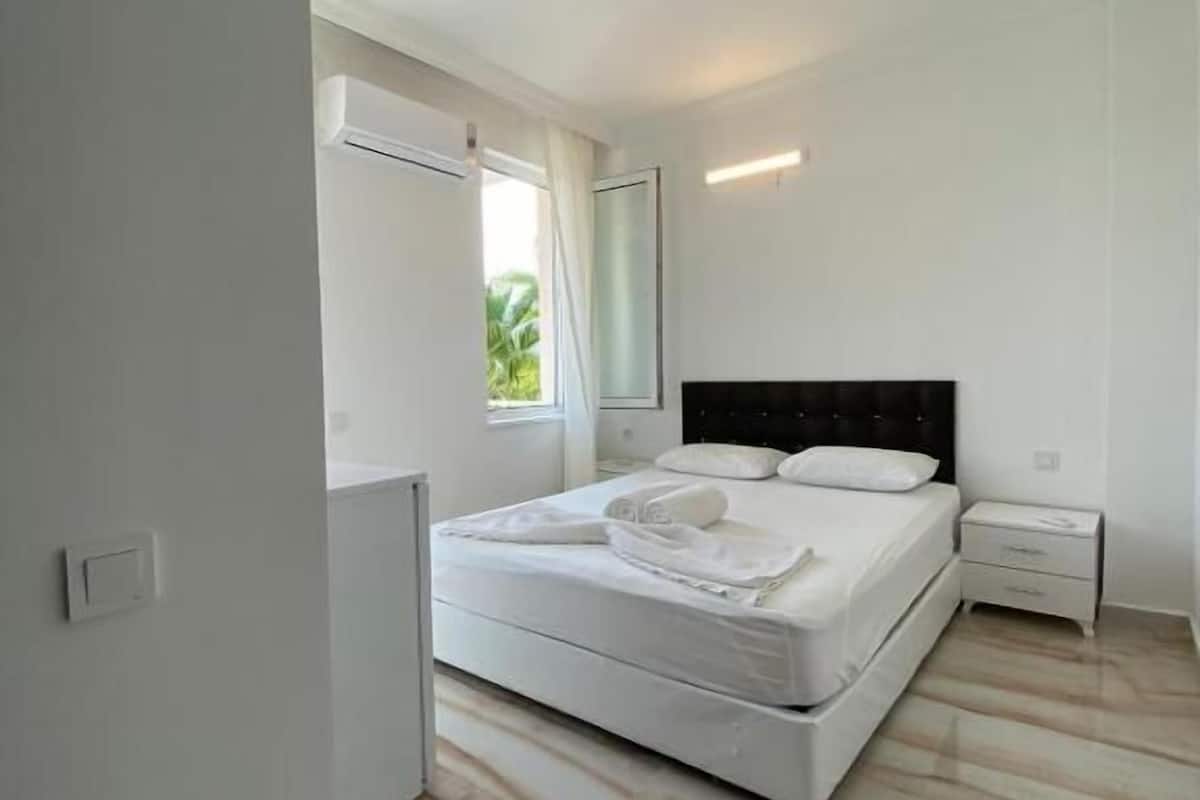 A modern bedroom with a large bed, a bedside table, and a window with curtains.