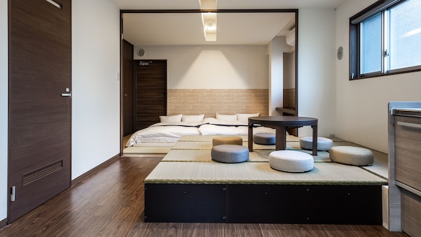 A modern hotel room with a large bed, a small table, and ottomans. - Temple Hotel Shoden-ji (Tokyo)