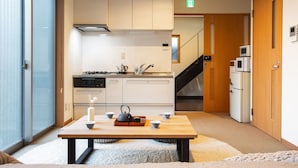 A modern kitchen with a wooden table, a kettle, cups, and a candle. - Temple Hotel Shoden-ji (Tokyo)