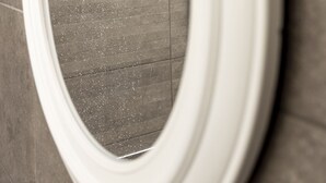 Un inodoro con asiento y tapa blancos, un chorro de agua visible y un suelo de baldosas.