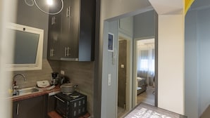 Una cocina compacta con armarios oscuros, horno integrado y un lavamanos pequeño.