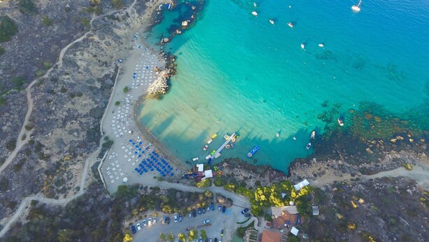 Luftaufnahme einer Küstenregion mit Strand, Booten und einer Marina.