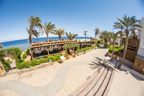 A beachfront resort with a wooden deck, palm trees, and a view of the sea. - Penguin Village Dahab (Dahab)