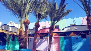 A courtyard with palm trees, colorful buildings, and a checkered floor. - Penguin Village Dahab (Dahab)