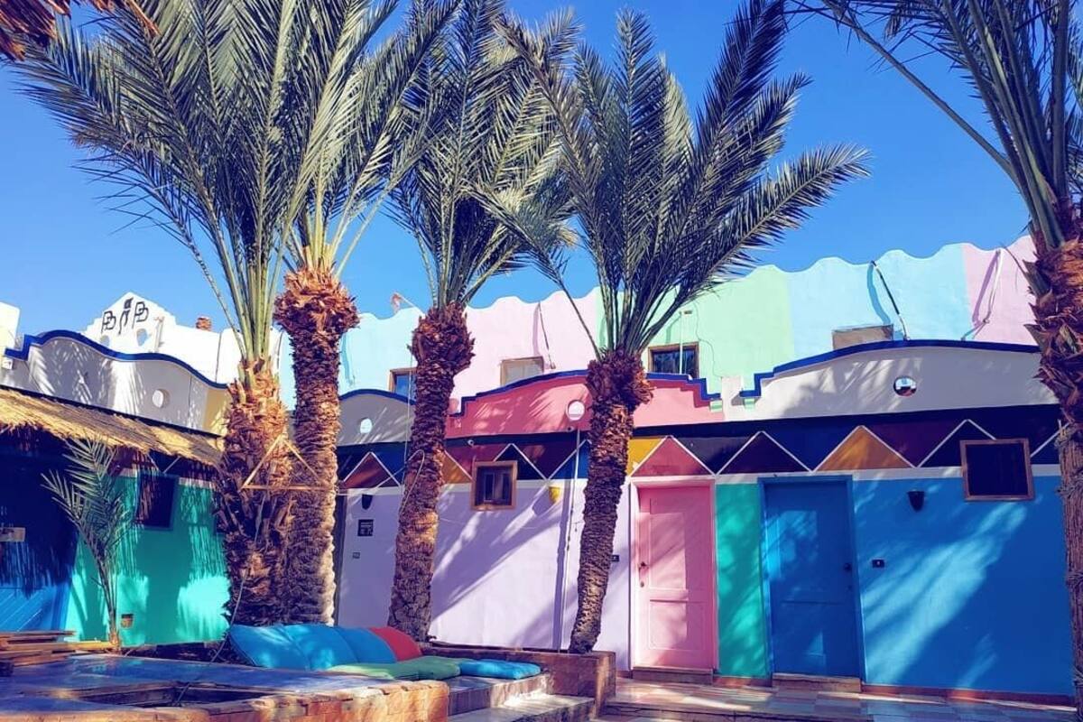 A courtyard with palm trees, colorful buildings, and a checkered floor.