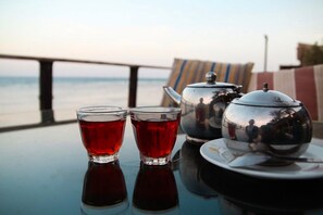 A table with two glasses of red tea, a teapot, and a reflective bowl on a table with a view of the sea. - Penguin Village Dahab (Dahab)