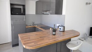 A modern kitchen with grey cabinetry, a wooden countertop, a microwave, a toaster, and a sink. - Comfortable villa - 3 rooms - PRIVATE swimming pool in a quiet location in Nice (NICE)