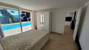 A bedroom with a bed, a wardrobe, and a view of a swimming pool. - Comfortable villa - 3 rooms - PRIVATE swimming pool in a quiet location in Nice (NICE)