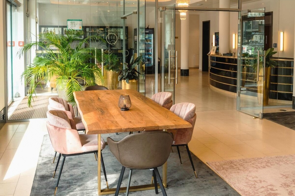 Una sala de conferencias moderna con una mesa de madera, sillas acolchadas y un separador de vidrio.