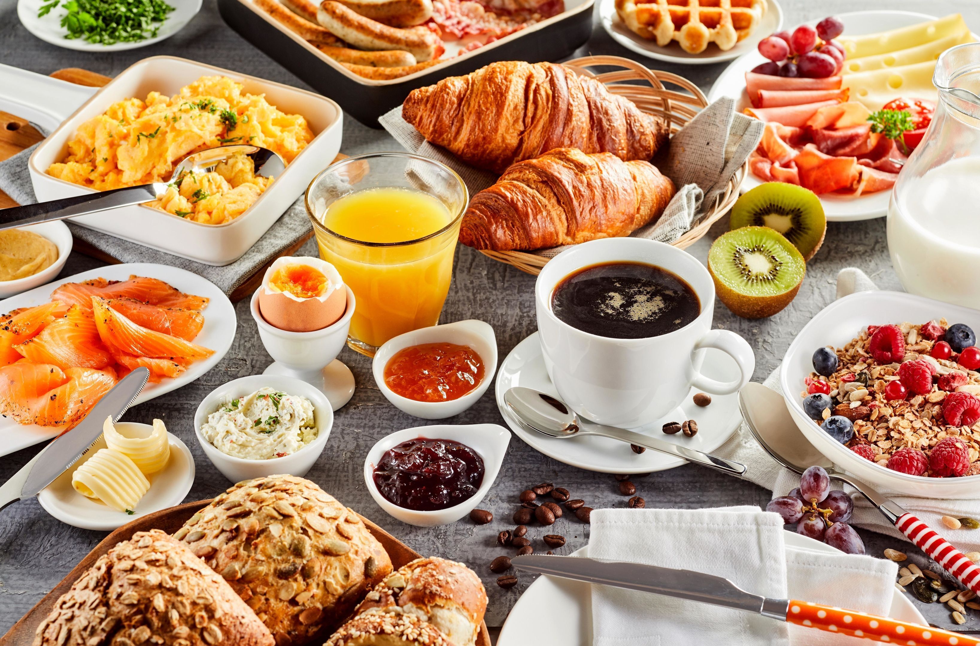 Un buffet de petit-déjeuner proposant une variété d’aliments, notamment des croissants, du saumon fumé et des fruits frais.