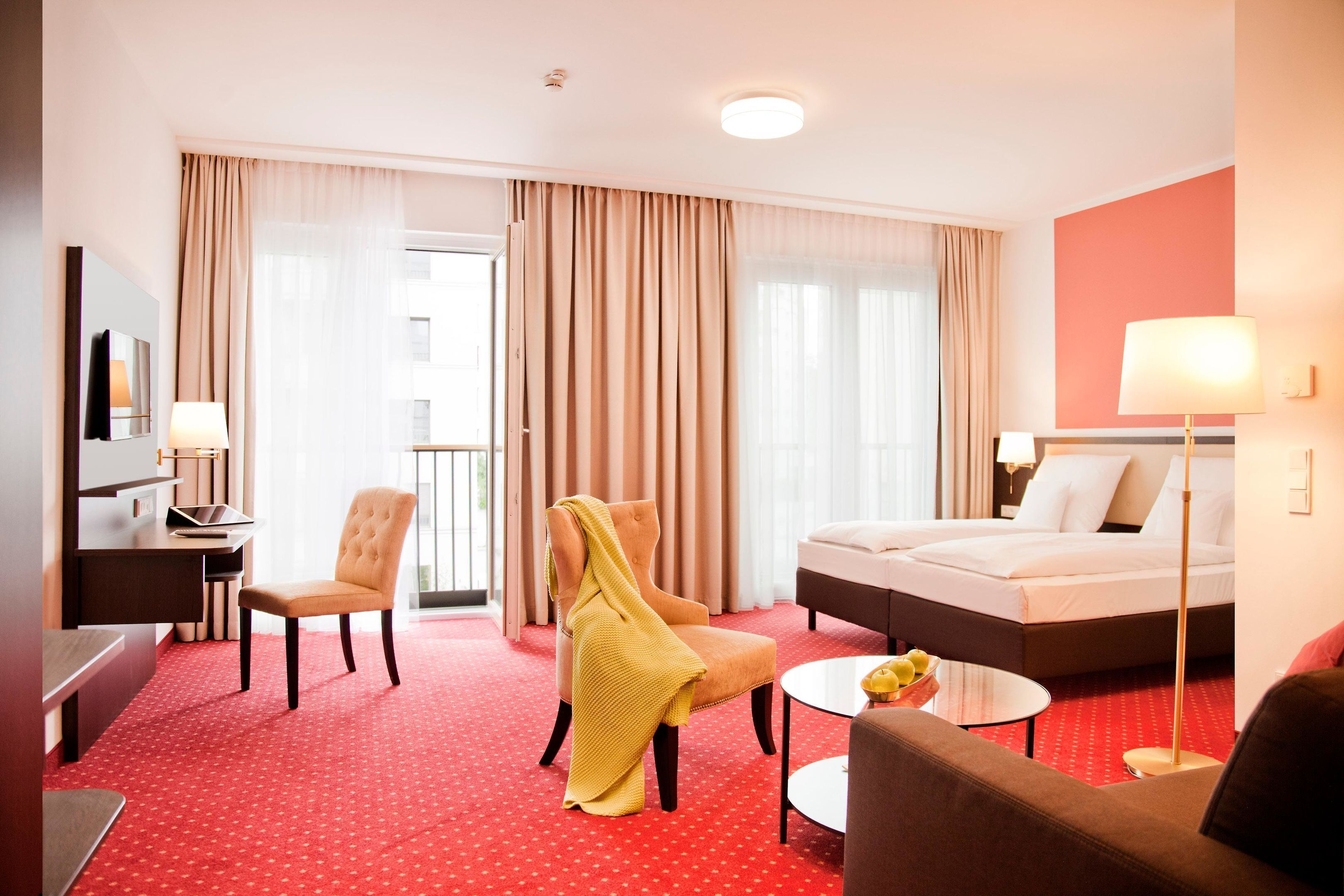 Una habitación de hotel con cama, escritorio, silla, sofá y una mesita.