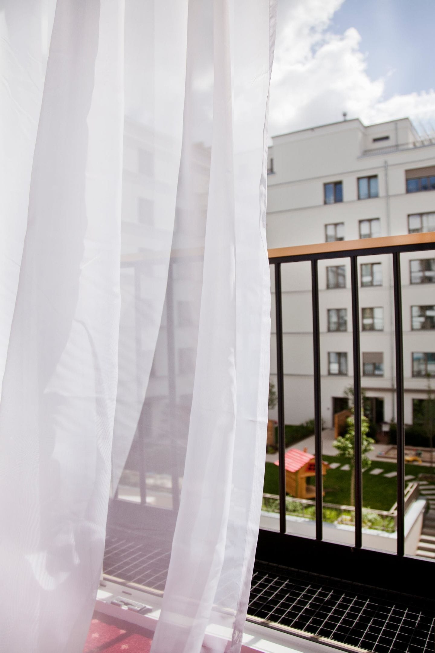 Un balcón con vistas a un edificio y un pequeño jardín.