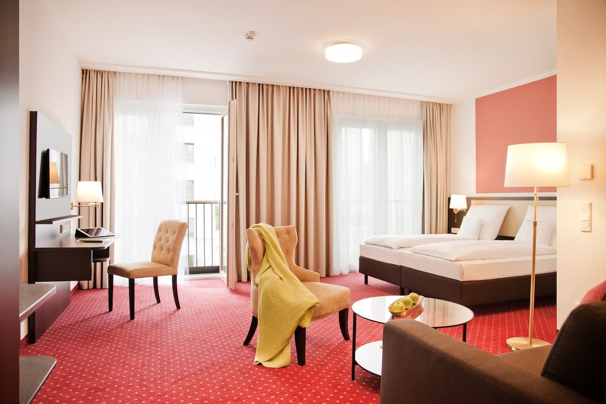 Hotellihuone, jossa on sänky, työpöytä, tuoli, sohva, pieni pöytä ja lamppu.