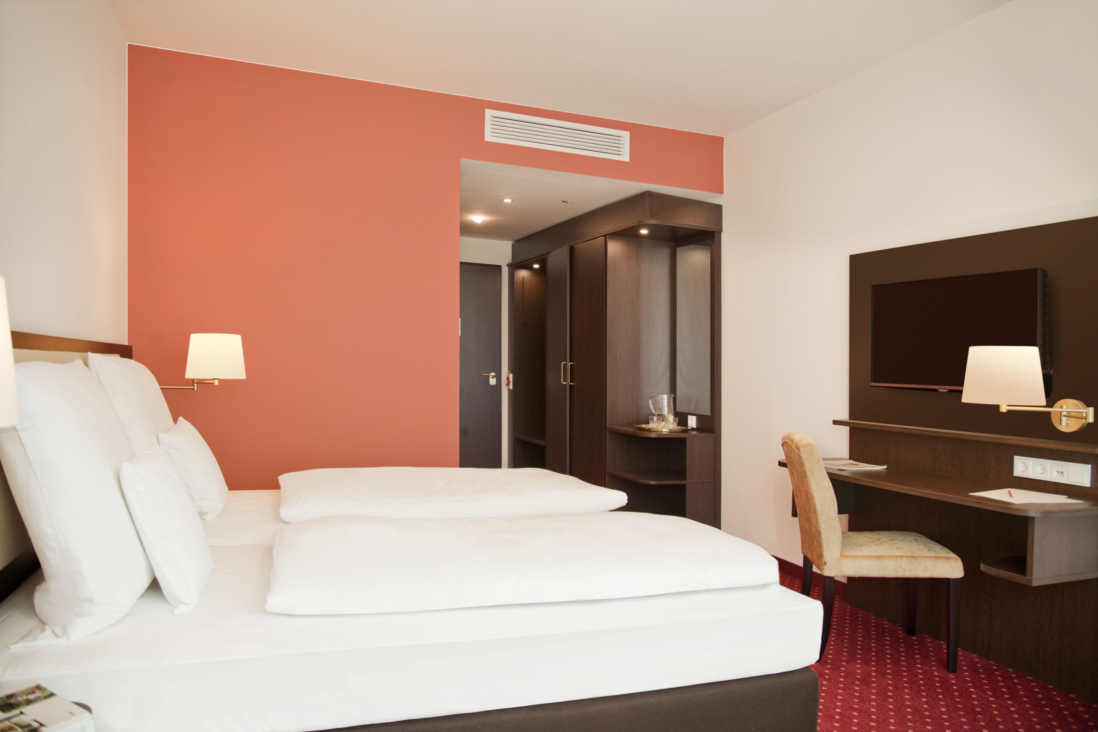 Une chambre d’hôtel avec un lit, un bureau, une chaise, une télévision et une porte de salle de bain.