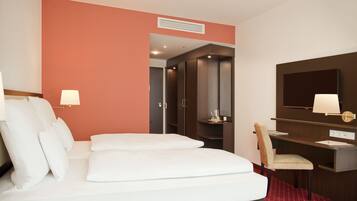 Une chambre d’hôtel avec un lit, un bureau, une chaise, une télévision et une porte de salle de bain.