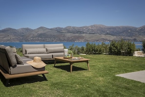 Relax in a serene outdoor space with a sofa, woven basket, and coffee table overlooking a scenic view.