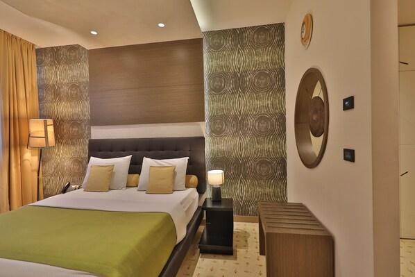 Relax in a spacious room with a large bed, nightstand, and wall clock.