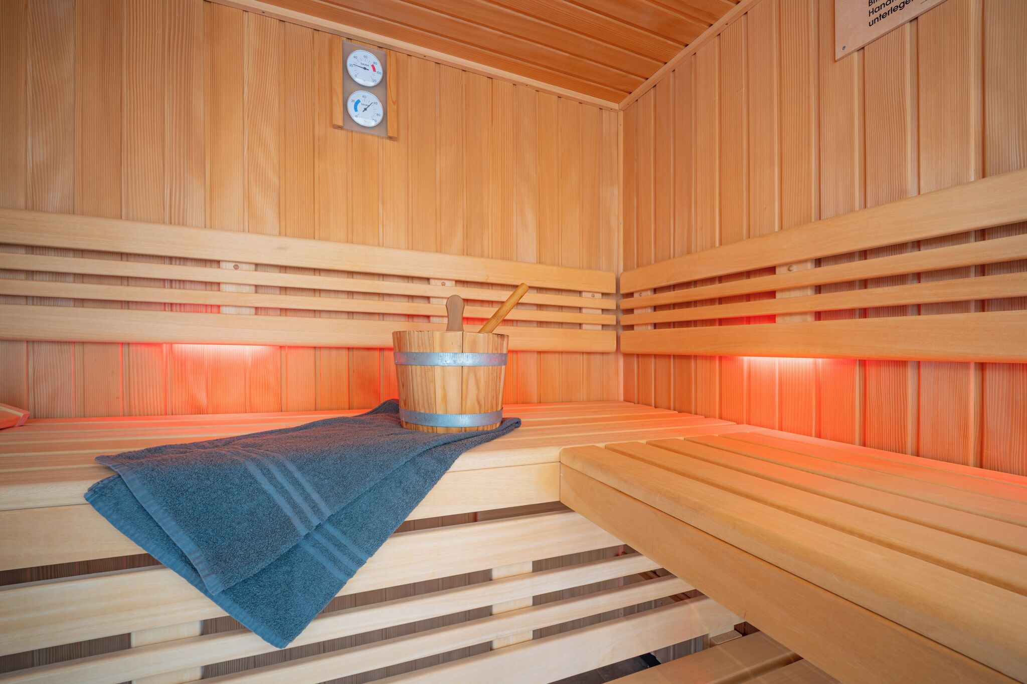 Un sauna avec des bancs en bois et un seau en bois.