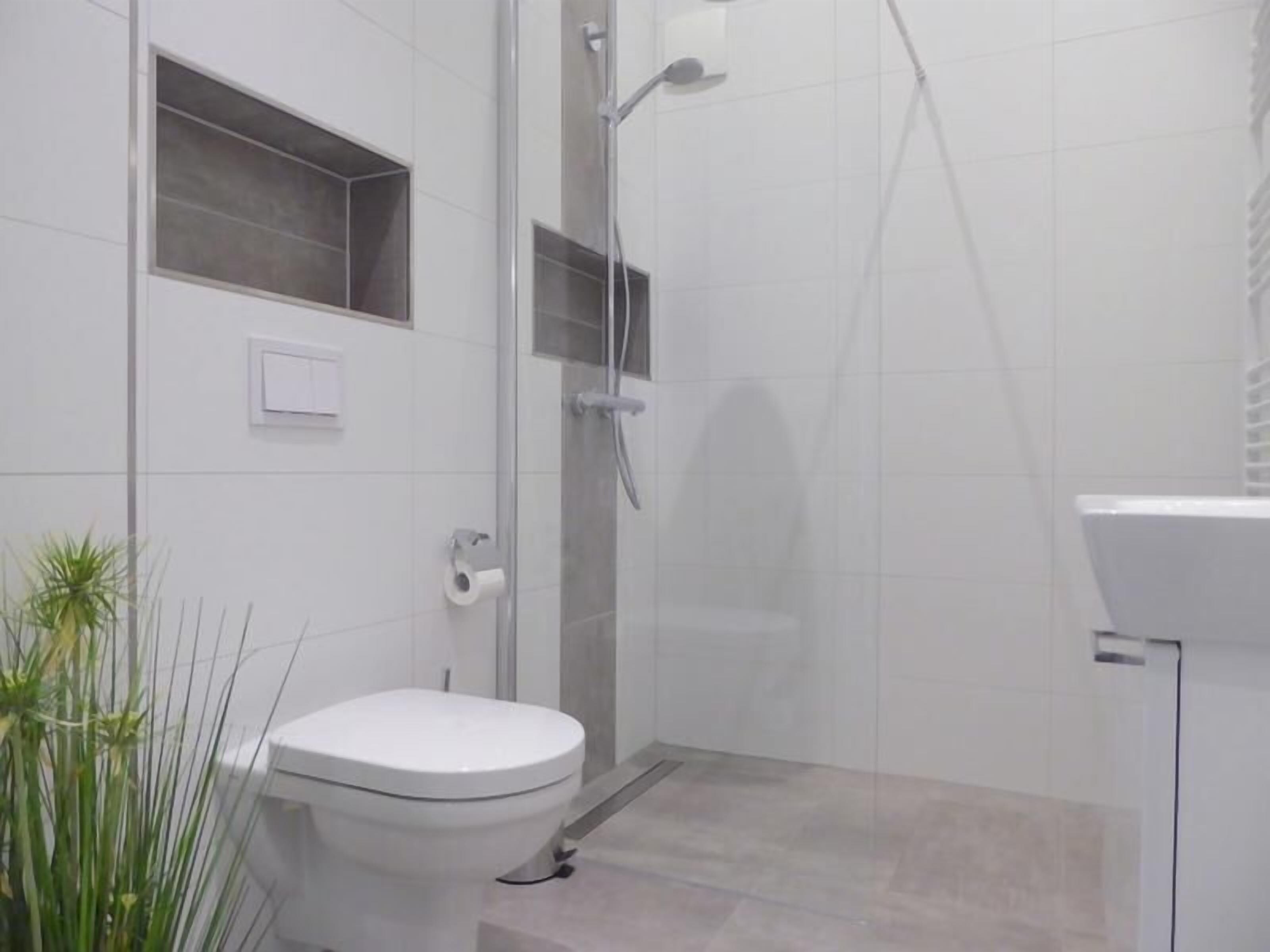 Une salle de bain moderne équipée de toilettes, d’une douche à parois de verre et d’un lavabo.