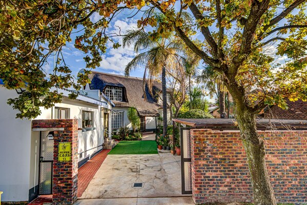 A residential property with a thatched roof house, a brick gate, and a well-maintained lawn.
