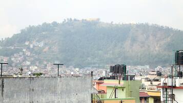 Paesaggio urbano con una collina in evidenza sullo sfondo, caratterizzato da edifici residenziali e alcune strutture sparse.