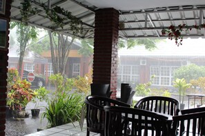 Un patio couvert agrémenté de piliers en briques, de plantes en pot et de mobilier d’extérieur.