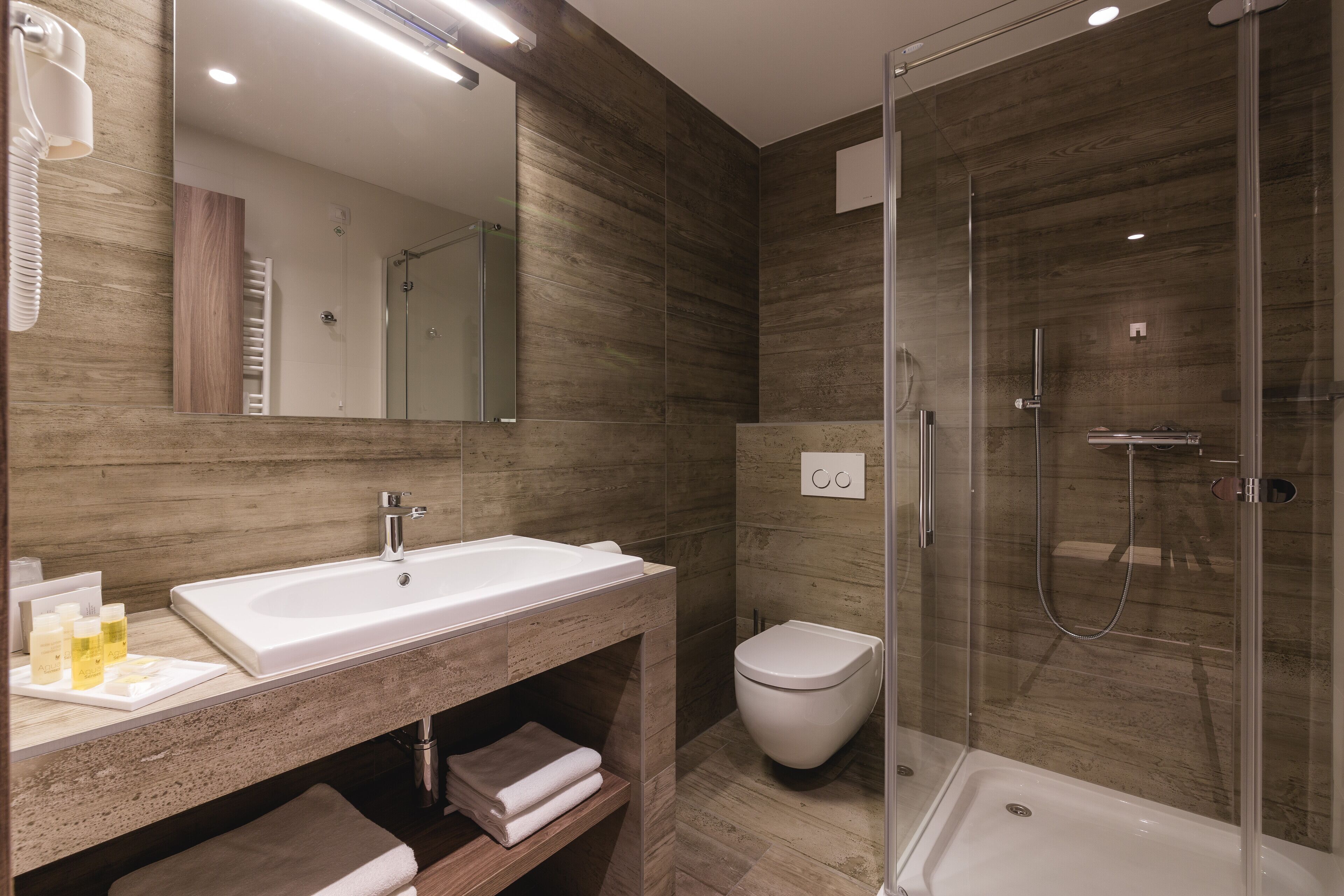 A modern bathroom with a large sink, a toilet, and a glass-enclosed shower.
