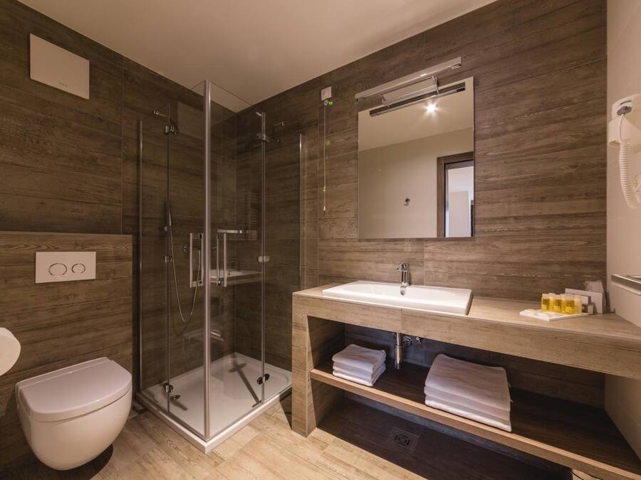 A modern bathroom with a glass-enclosed shower, a wooden vanity with a sink, and a toilet.