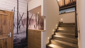 Una escalera de madera con un estante fijado a la pared y una puerta con un revestimiento texturizado.