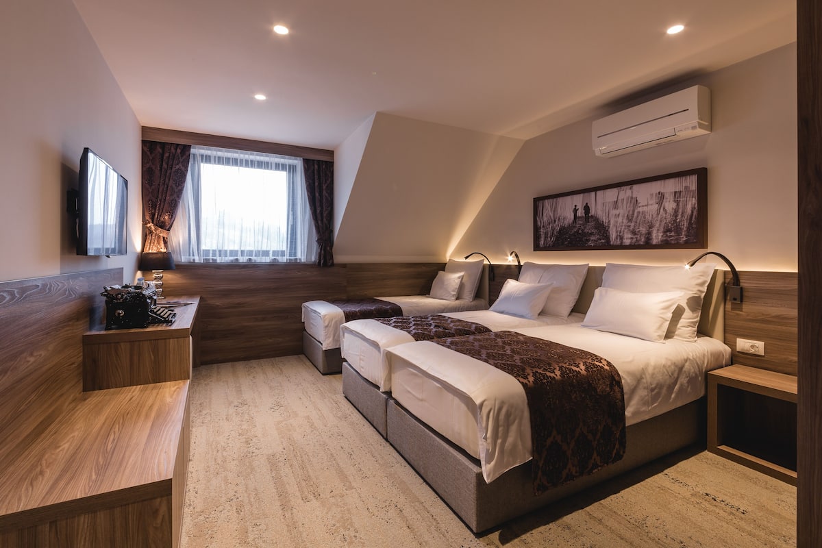 A modern hotel room with a large bed, a desk, and a television.