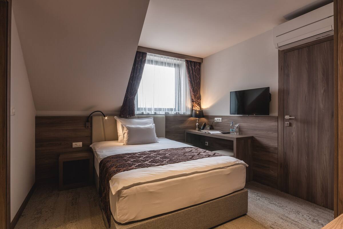 A modern bedroom with a bed, bedside table, lamp, TV, and wardrobe.