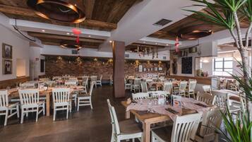 A spacious restaurant with wooden tables and chairs, exposed brick walls, and hanging decorations.