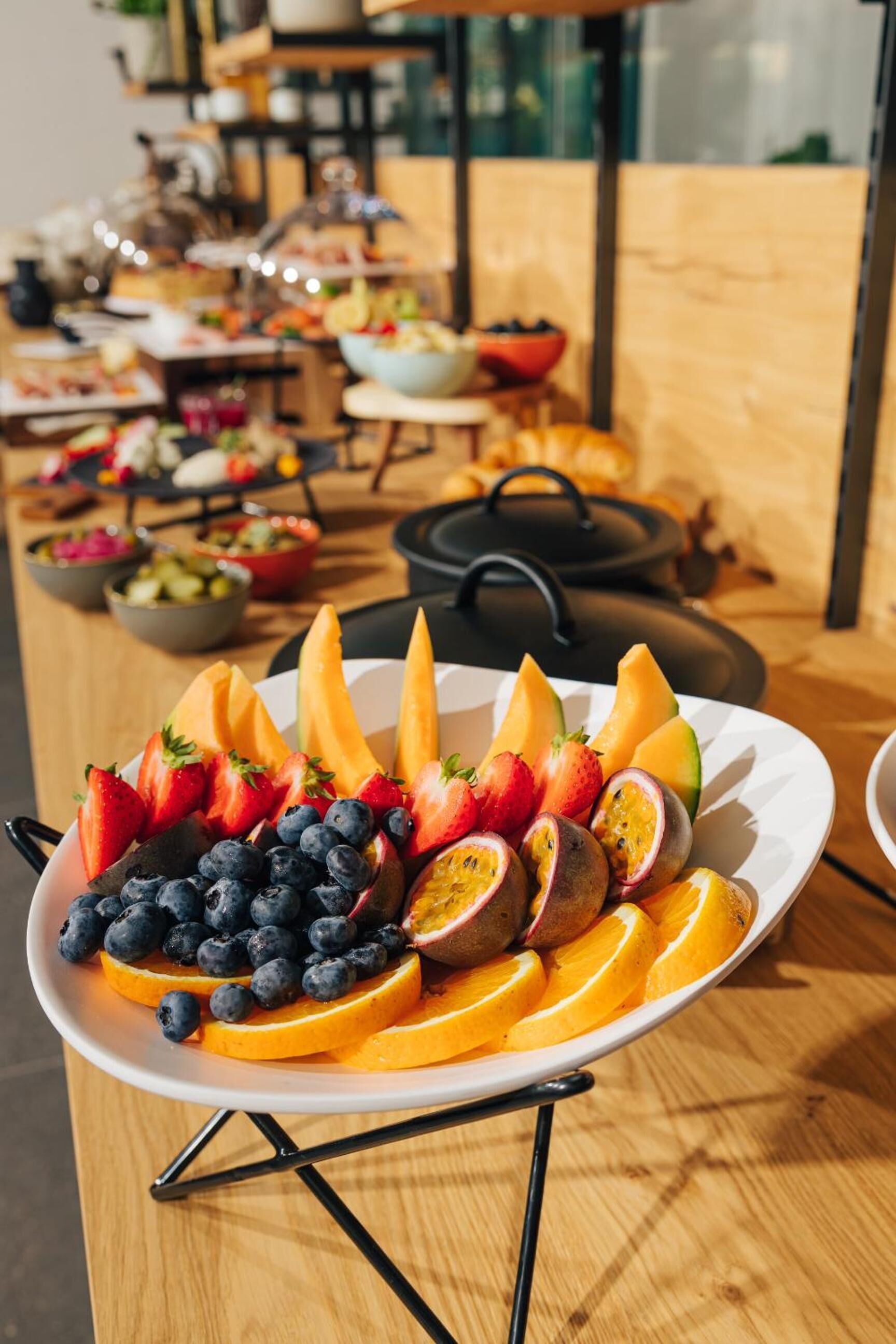 Une assiette de fruits est posée sur une table, avec un fond en bois et un pot en arrière-plan.