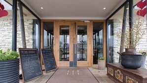 Entrada de un restaurante con fachada de piedra, puertas de madera y un menú en la pizarra.