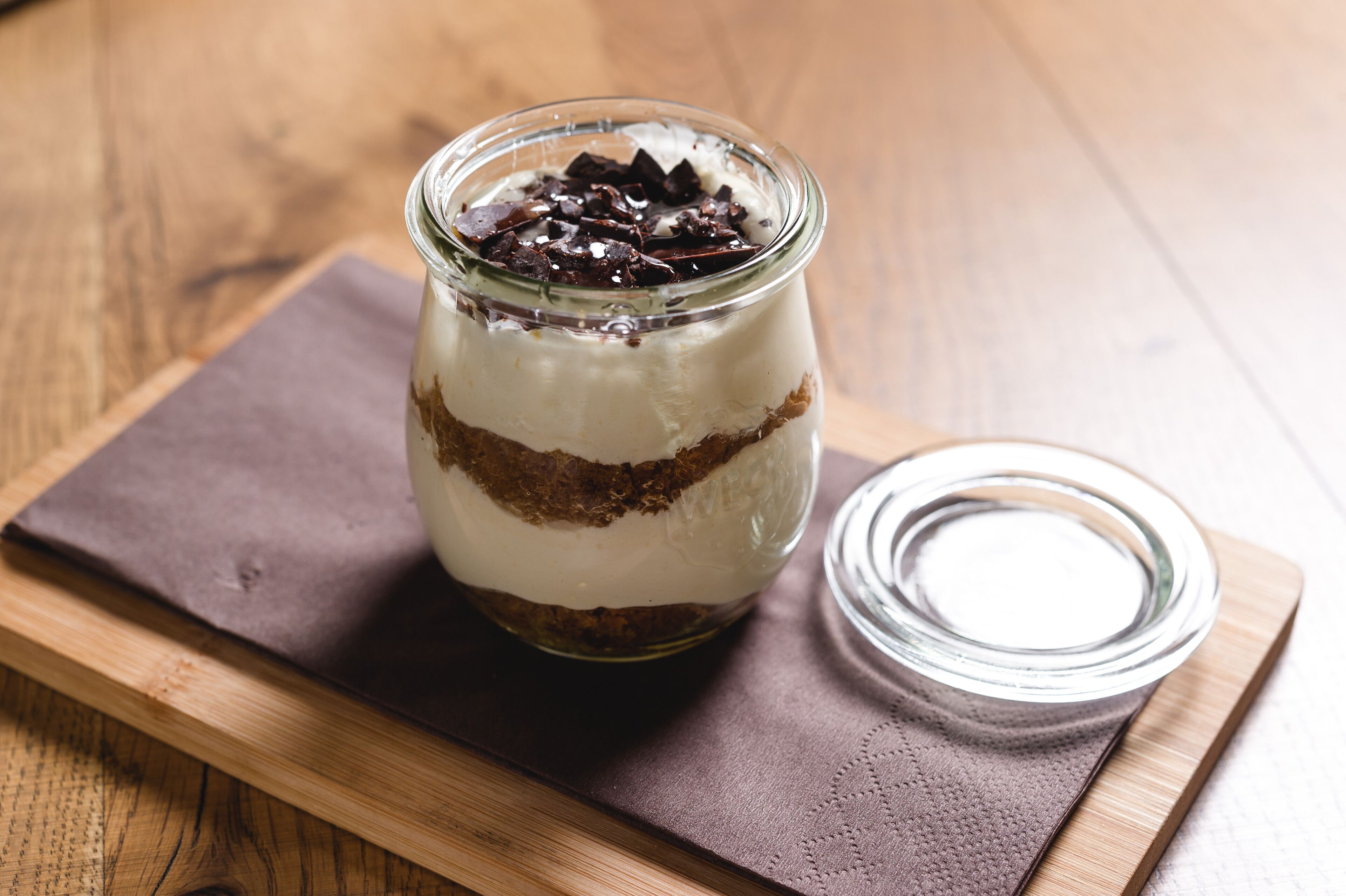 Un postre en capas dentro de un tarro de vidrio sobre una tabla de madera.