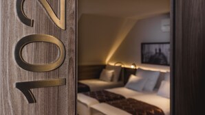 Una habitación de hotel con una cama, una mesita de noche y una lámpara de pared.