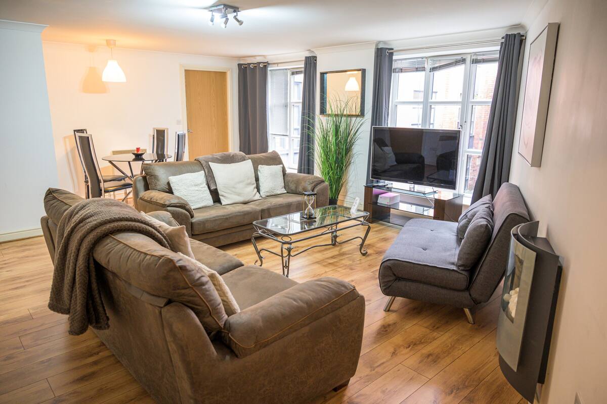 A living room with a brown sofa, a glass coffee table, and a flat-screen TV.